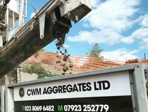 An aggregate delivery pipe depositing aggregate into a CWM trailer